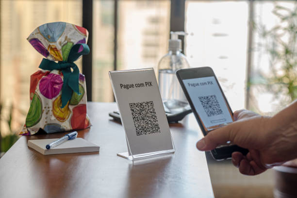 Hand holding cell phone with QR Code for payment at the store with new Instant Payment modality - “PIX” stock photo