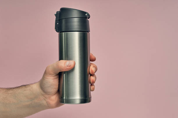 istock Metal mug thermos in hand on a colored background. Hot drinks on the go. Thermo mug. 1279059085