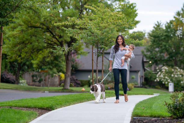 Pacific Islander mother holding her baby while walking the dog