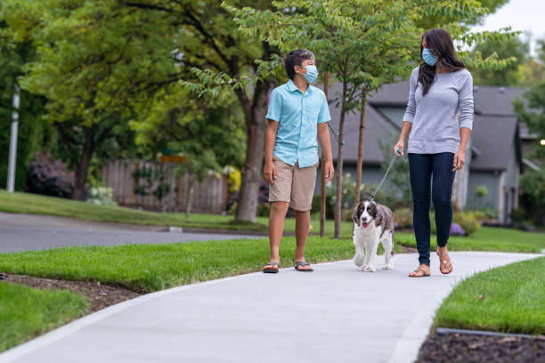 istock Mom and son wearing protective face masks walking their dog 1279059627