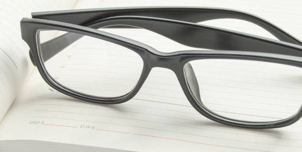 istock Stylish black reading glasses on an open diary, close-up banner 1279059751