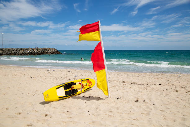 Surf lifesavers rescue board and flag on the beach at Cottesloe Cottesloe, Australia - October 7th 2020: Surf lifesavers rescue board and flag on the beach at Cottesloe western australia flag stock pictures, royalty-free photos & images