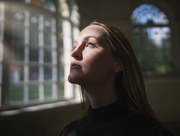 istock caucasian woman looking through window with face illuminated 1279061825