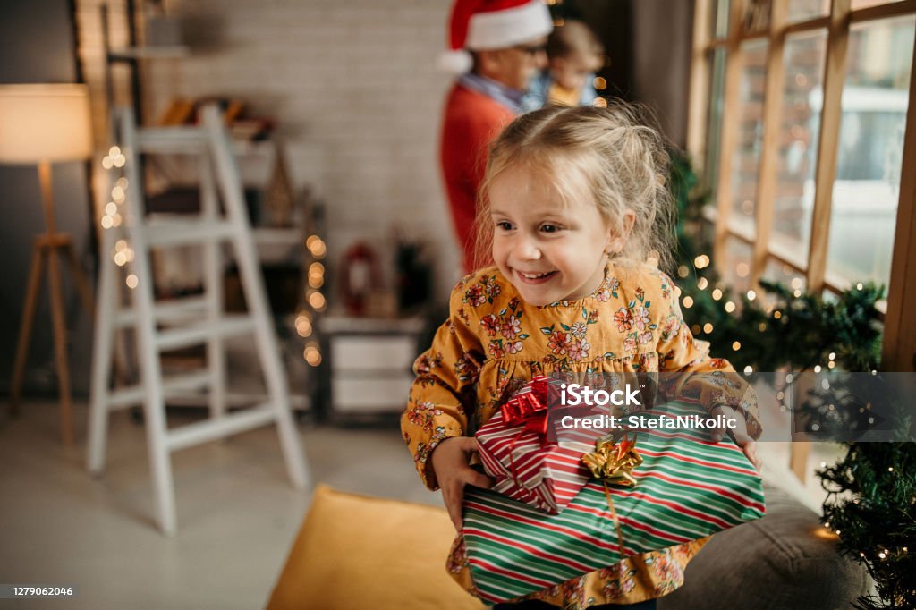 What we have inside the box Happy multi generation family celebrating Christmas in warmth of their home Child Stock Photo