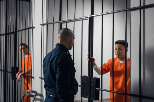 The prison warden puts the prisoner behind bars after the court verdict and locks the cell stock photo