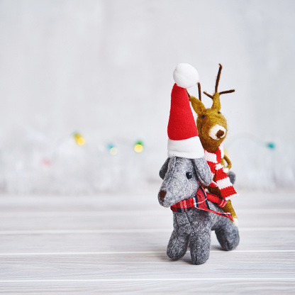 Christmas background with little gray felt dog giving reindeer a piggy back