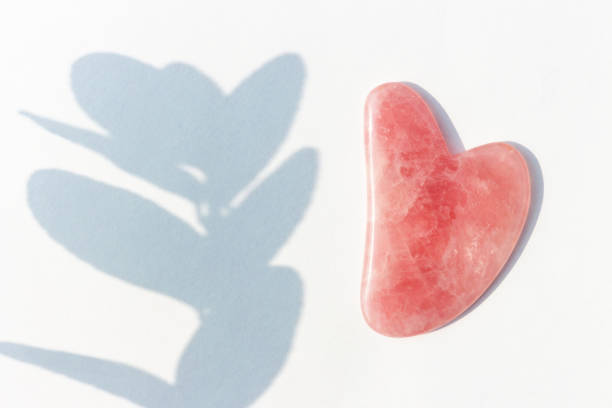 istock Pink massager gua sha and shadow on white background top view. 1279067014
