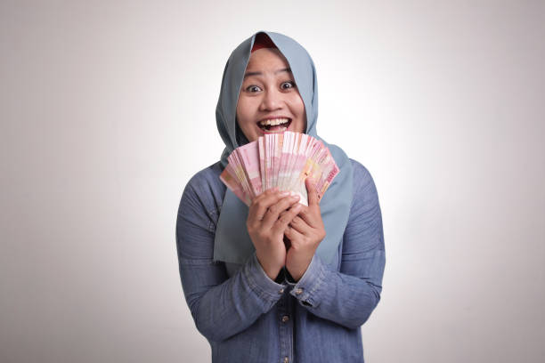 femme musulmane indonésienne retenant l’argent de rupiah - indonesian currency photos et images de collection