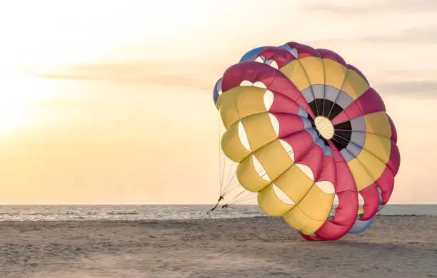 Photo of Beautiful photo of colorful parasailing parachute anchored on secluded beach for tourists loving adventure sports. Photo is well isolated. Concept of Growth, Independence, Resistance, lockdown etc.
