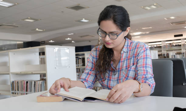 foto di una ragazza bella e intelligente con gli occhiali che studiano duramente in biblioteca pubblica per i prossimi esami. ogni studente universitario può connettersi a questa immagine per vari scenari. - bibliophile foto e immagini stock