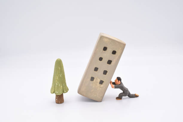 istock A miniature leaning building made of clay and a man supporting it. 1279090503
