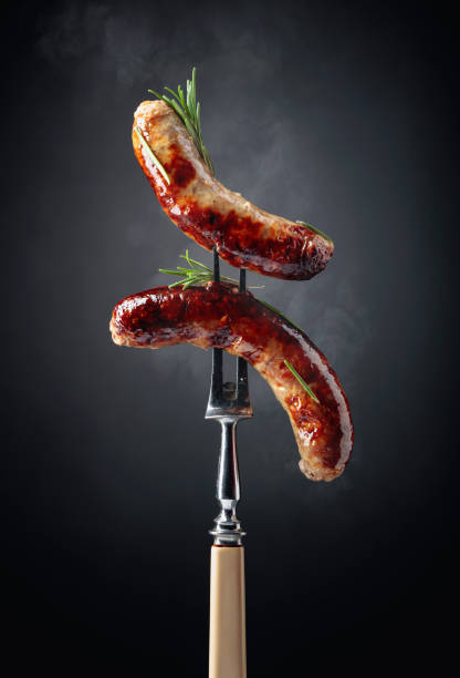 Grilled Bavarian sausages with rosemary. Grilled Bavarian sausages with rosemary.  Sausages  on a fork sprinkled with rosemary. 1528 stock pictures, royalty-free photos & images