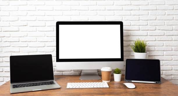 istock Mockup blank screen computer on a wooden desk. desktop empty white screen, with workspace and office supplies on table 1279092645