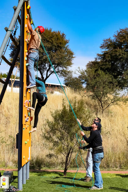 Woman smiling, wearing helmet and harness, navigating an adventure park ropes course.