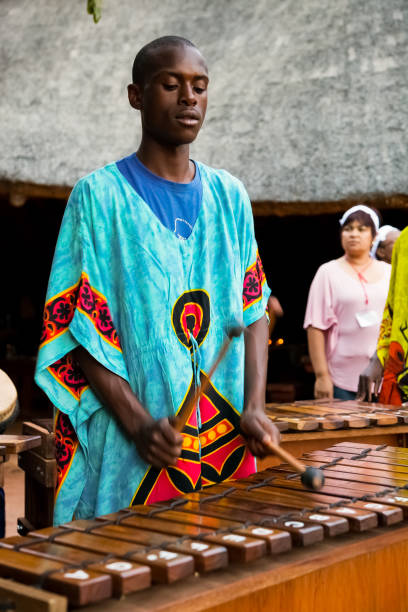 uomini africani che suonano tamburi tradizionali per i turisti - african descent african culture drum history foto e immagini stock