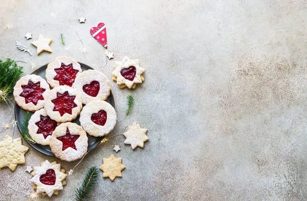 Plate with Christmas or New Year shortcrust cookies with red jam. Traditional festive Austrian cookies with jam. Linzer cookies. Copy space.