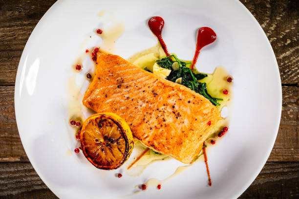 istock Fried salmon fillet and vegetables served on wooden table 1279097662