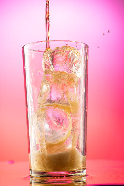 pour cola into a glass with pieces of pure real ice on a red purple gradient background