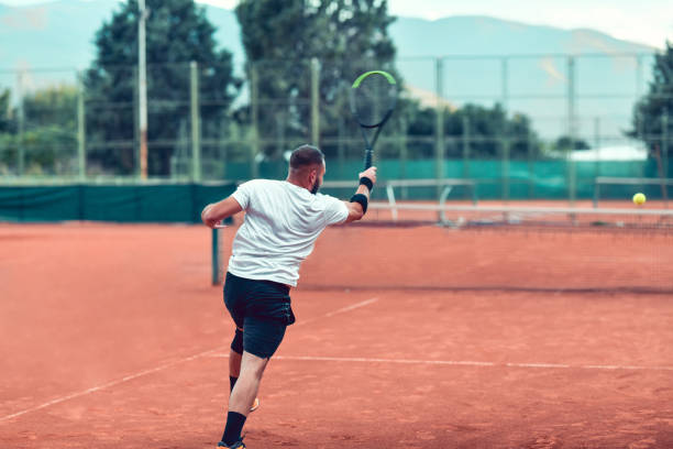 istock Handsome Tennis Player Hitting Ball With Full Force During Match 1279098575