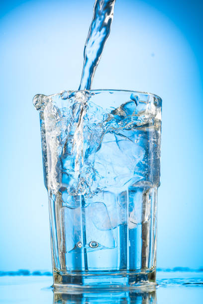 istock pour clear water into a glass with chunks of pure real ice on a blue gradient background 1279098708
