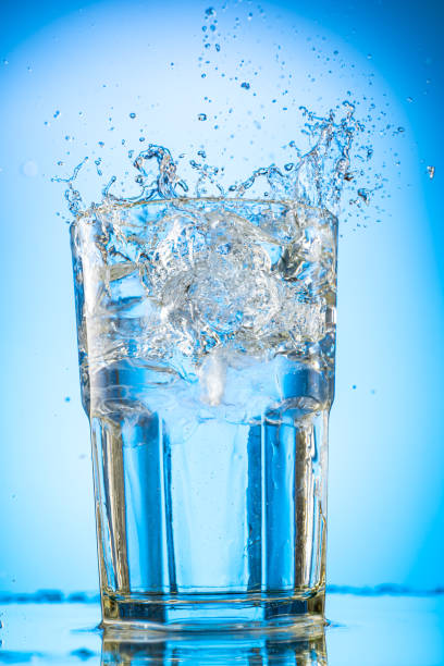 istock pour clear water into a glass with chunks of pure real ice on a blue gradient background 1279098770