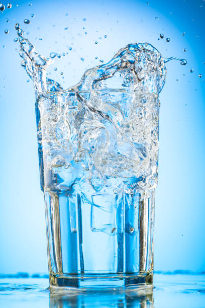 istock pour clear water into a glass with chunks of pure real ice on a blue gradient background 1279098914