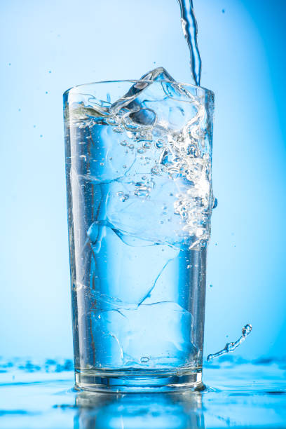 istock pour clear water into a glass with chunks of pure real ice on a blue gradient background 1279098935