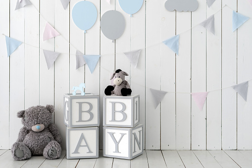 Word baby on wooden cubes near toys and decorated wall