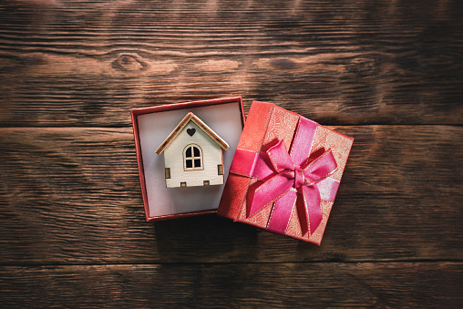 House as a gift concept. A small house in a gift box on the woodent able background.