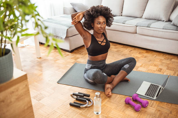istock Young black woman sitting on the floor at home stretching. 1279110959
