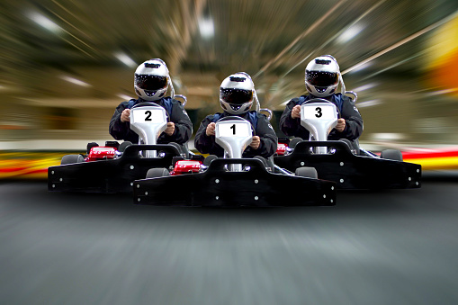 go kart indoor, cart racing fast, car where gokarting, we speed racing, racers banner. Three riders Go kart speed rive indoor race on the background of the track Copy space.
