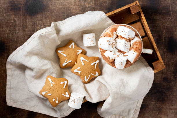 istock Hot cocoa or hot chocolate with marshmallows in a ceramic Cup on a wooden tray surrounded by gingerbread. Top view with space for text 1279113680