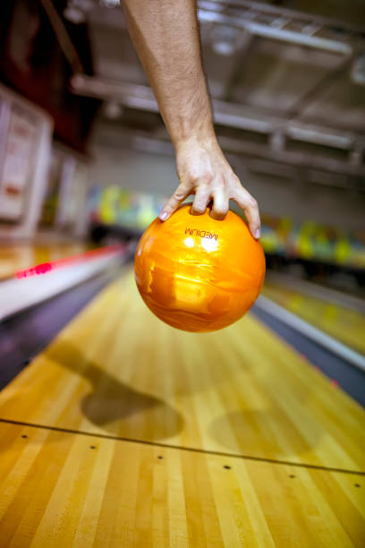 Bowling ball at hand of man background bowling alley Bowling ball orange at hand of man background bowling alley bowling alley wood stock pictures, royalty-free photos & images