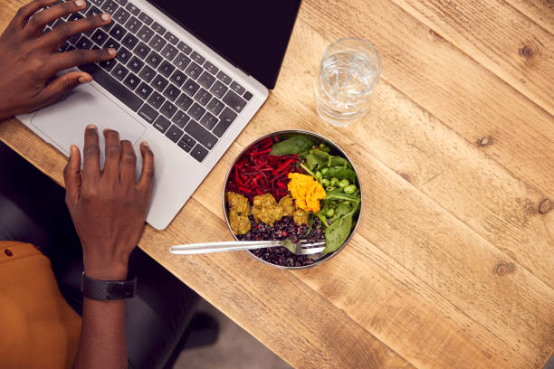 close up empresaria trabajando en el ordenador portátil mientras come almuerzo vegano en la mesa de madera - lunch business office business lunch fotografías e imágenes de stock