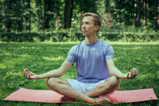 istock Young man meditating in the park 1279115001