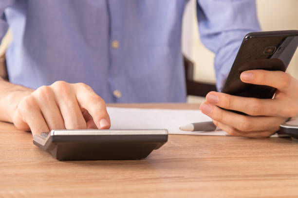 istock hands with calculator and mobile phone in the foreground 1279116574