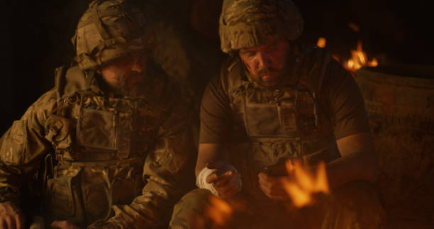 istock Squad mates browsing smartphone and talking near campfire 1279118177