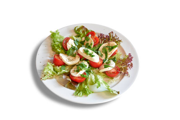White plate with tomatoes and mozzarella on salad. Isolated on white with clipping path