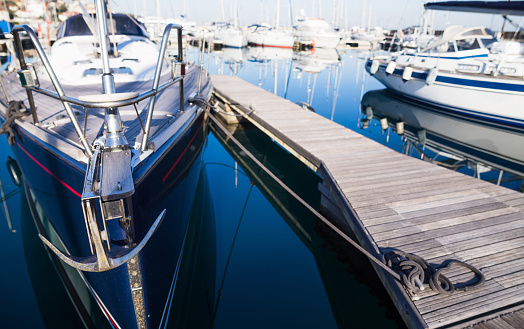 Two white identical boats with covered cabin moored in Boston Harbor with wooden piers protruding into the Atlantic Ocean with port trade and fishing infrastructure at twilight