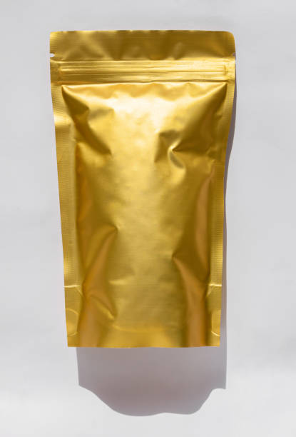 istock Golden metalized pouch bag with coffee beans top view with shadow isolated on white background. Food packaging flat lay. 1279122564