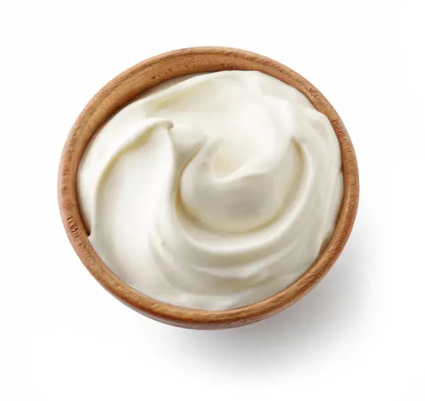 wooden bowl of whipped yogurt cream isolated on white background, top view