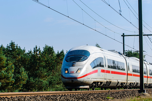 ICE train (Intercity-Express) driving on a railroad track trough a forest on the railway track between Amsterdam and Cologne.