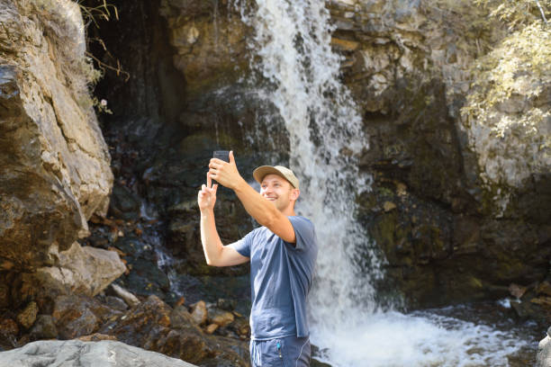 istock A man takes a selfie in front of a waterfall 1279124119