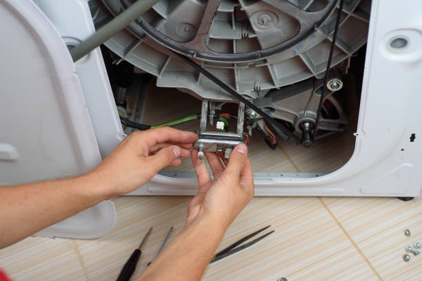 Handyman repairs the washer machine with wrench and screwdriver Handyman repairs the washer machine with wrench and screwdriver electrolux dishwasher repair stock pictures, royalty-free photos & images