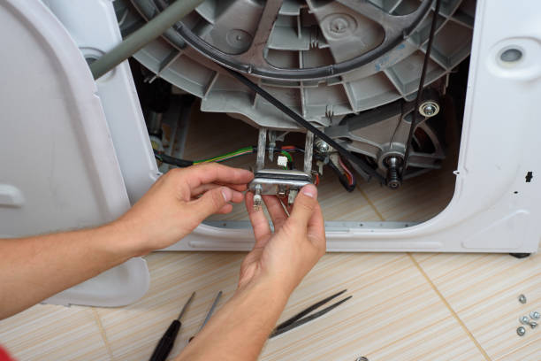 handyman repairs the washer machine with wrench and screwdriver - faulty imagens e fotografias de stock