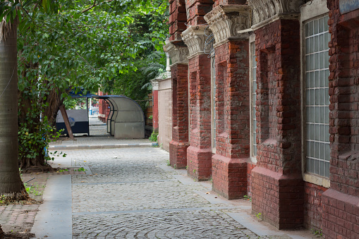 Empty pathway beside old building in kolkata west bengal during covid19 lockdown. beautiful green trees on other side of path.