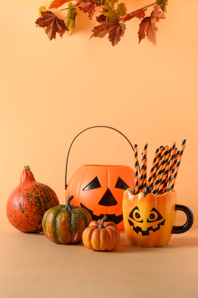 istock Halloween fun party decorations, candy bowl, pumpkins, sweets, mug with drinking straw on orange. Vertical composition. 1279125404