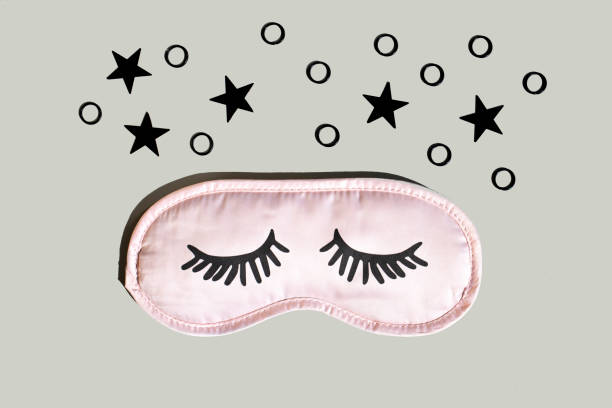 istock Pink sleep mask with eyelashes on a gray background with black stars. 1279125592