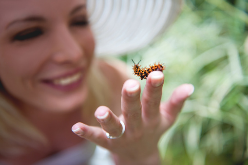 Smiling woman holding caterpillar on her finger