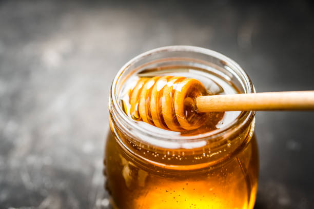 Jar with freshly harvested liquid honey on the old wooden table